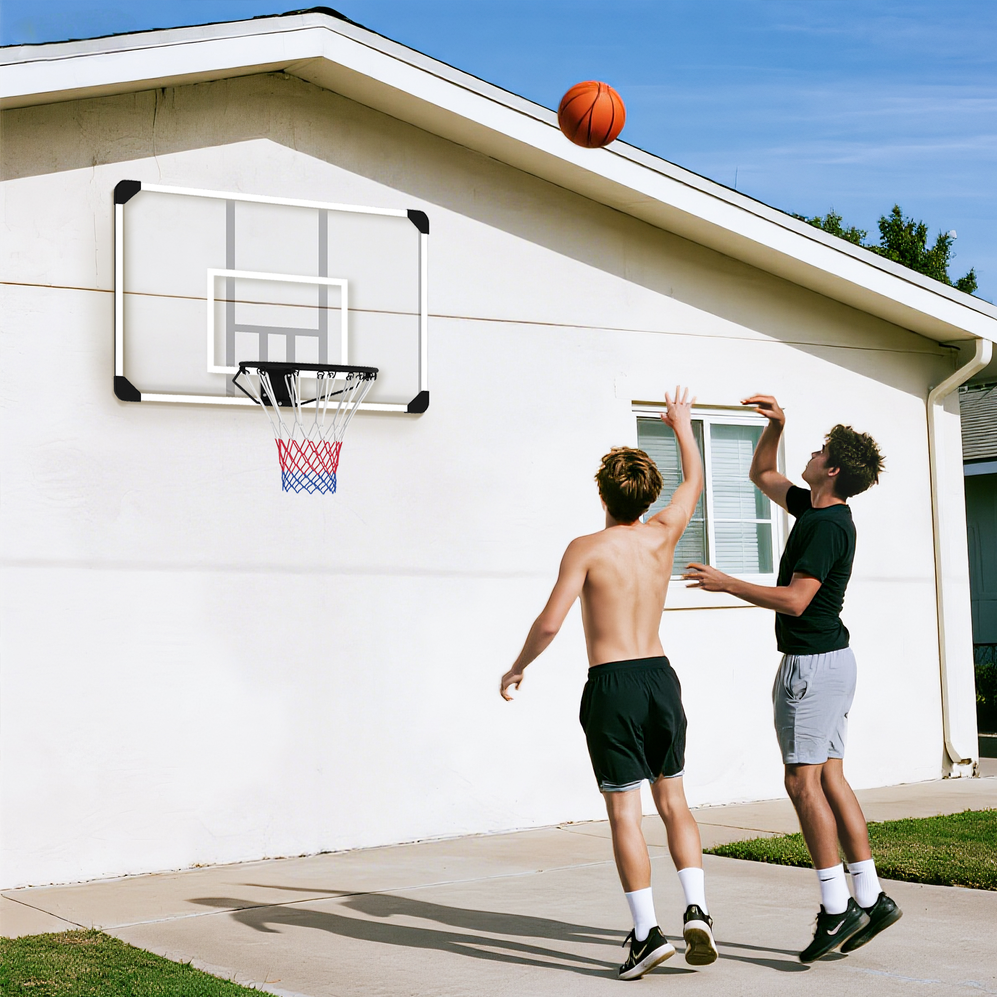 Dos jóvenes juegan al baloncesto frente a una pared blanca con canasta.