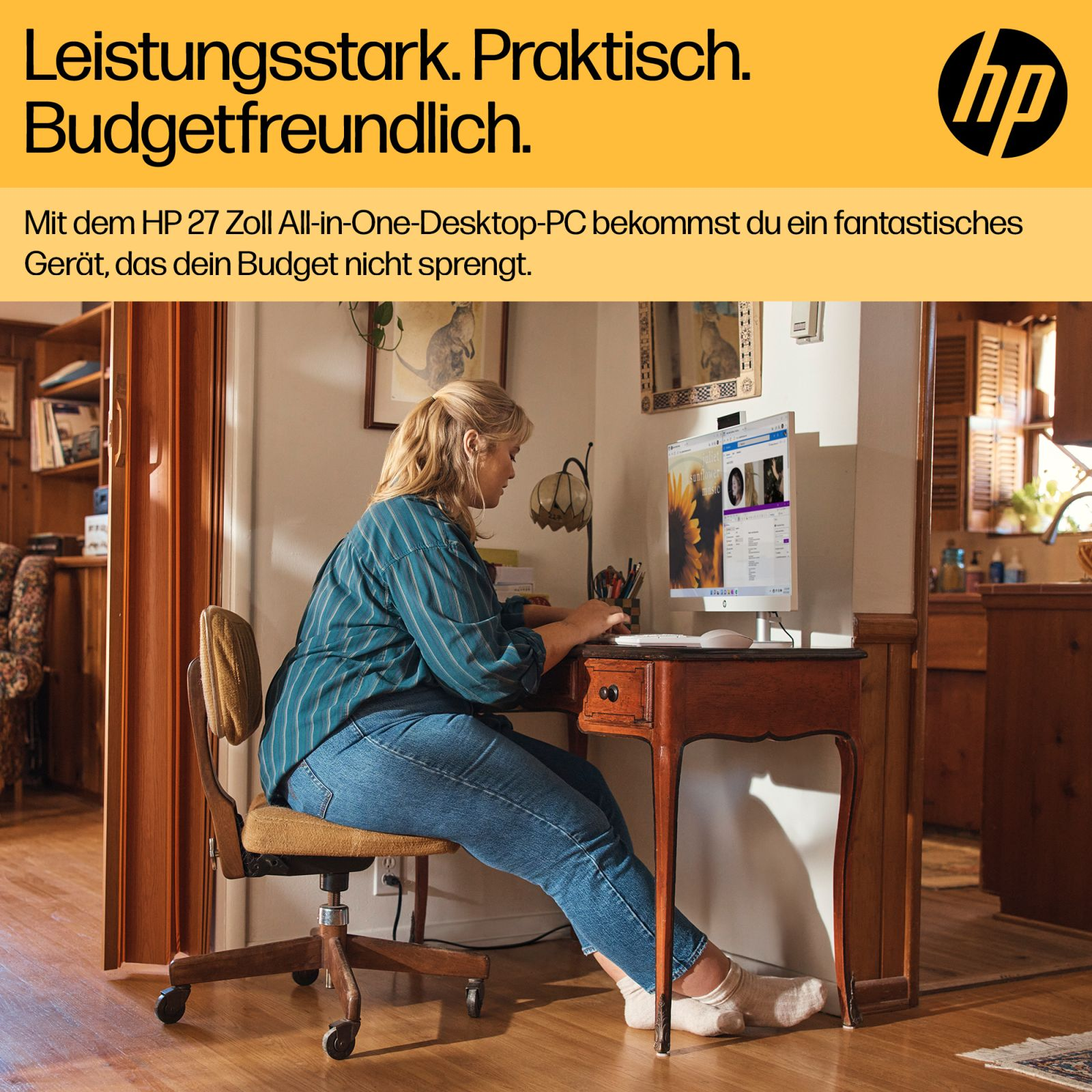 Eine Frau sitzt an einem Holztisch und arbeitet an einem weißen HP All-in-One-Desktop-PC.