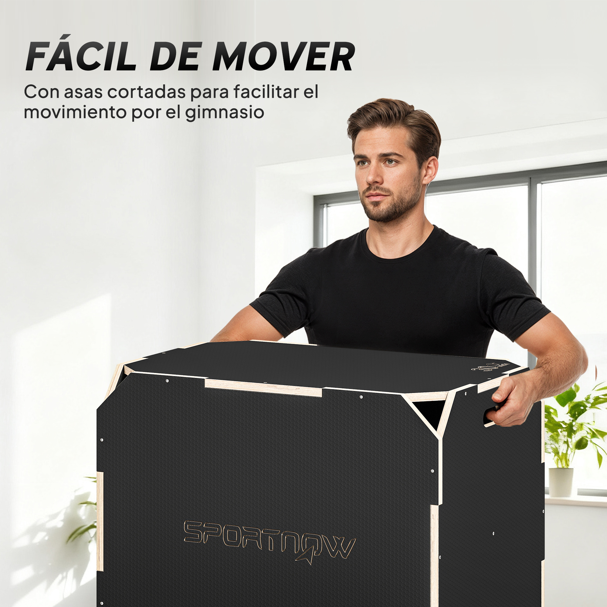Un hombre con camiseta negra transporta una gran caja deportiva negra con asas integradas en una habitación luminosa.