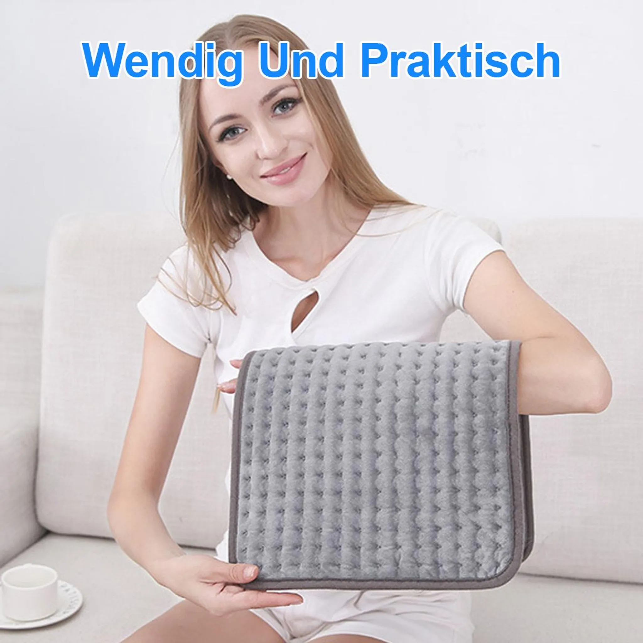 Eine blonde Frau sitzt auf einem Sofa und hält eine graue, gesteppte Heizmatte.