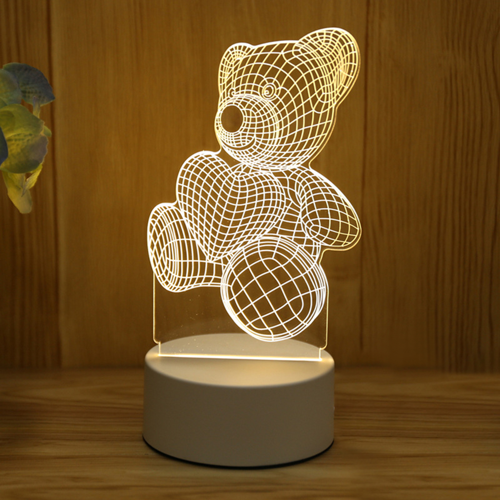 Eine leuchtende Acryllampe mit einem Gittermuster zeigt einen Teddybären, der ein Herz hält, auf einem Holzgrund.