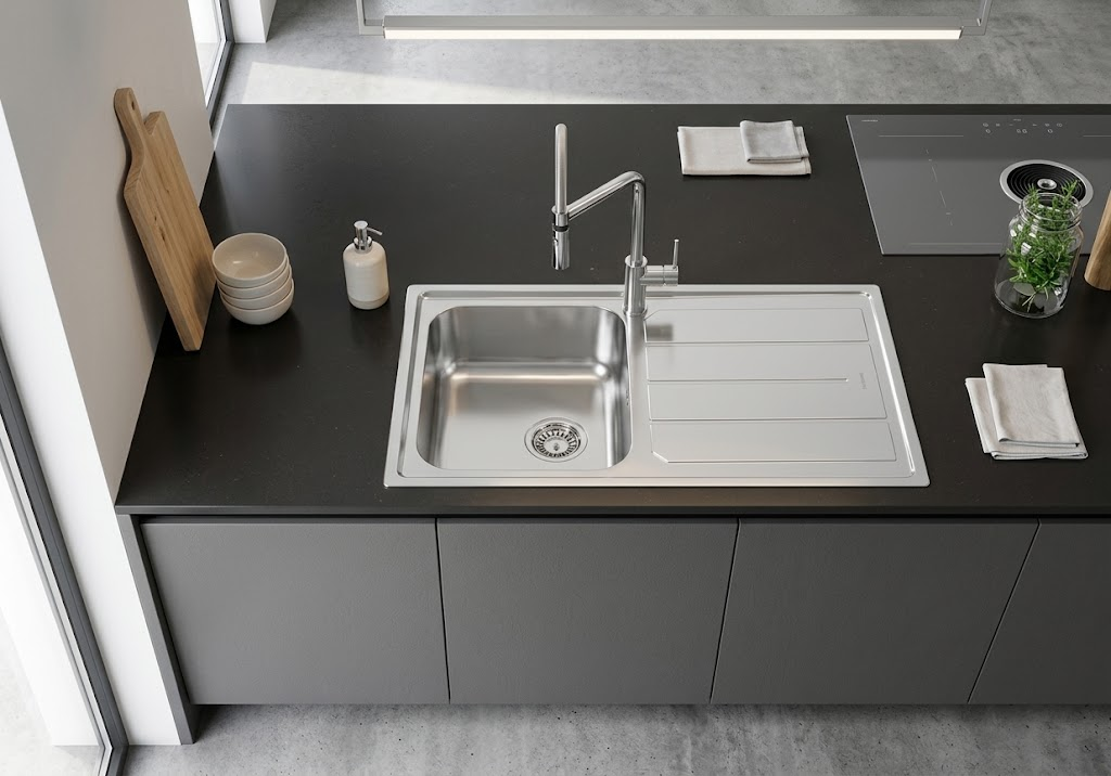 Moderno lavello in acciaio inox con rubinetto su piano cucina scuro, con utensili.