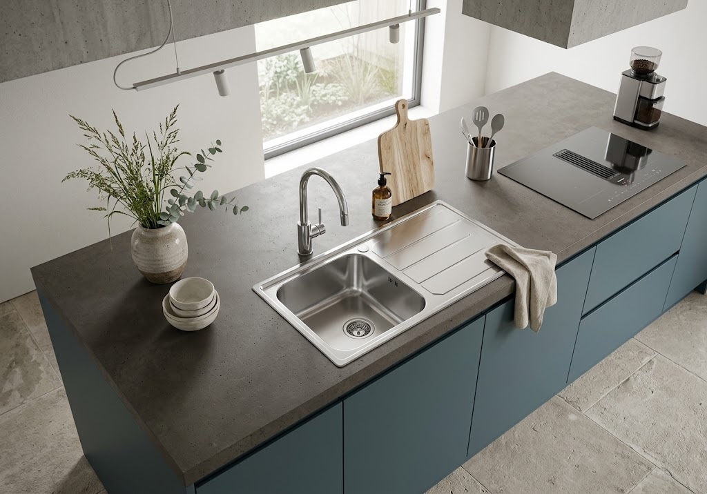 Moderna isola cucina con lavello in acciaio, piano di lavoro scuro e mobili verdi davanti a una finestra.