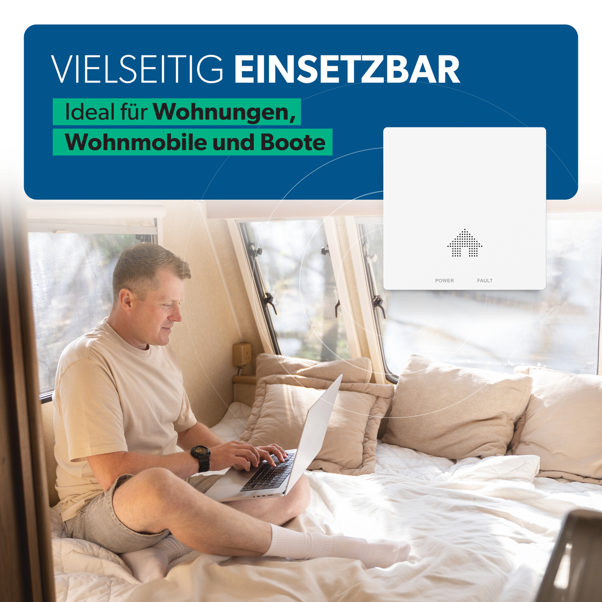 Ein Mann sitzt in einem Wohnmobil auf dem Bett und arbeitet an einem Laptop, daneben ein weißes Gerät an der Wand.