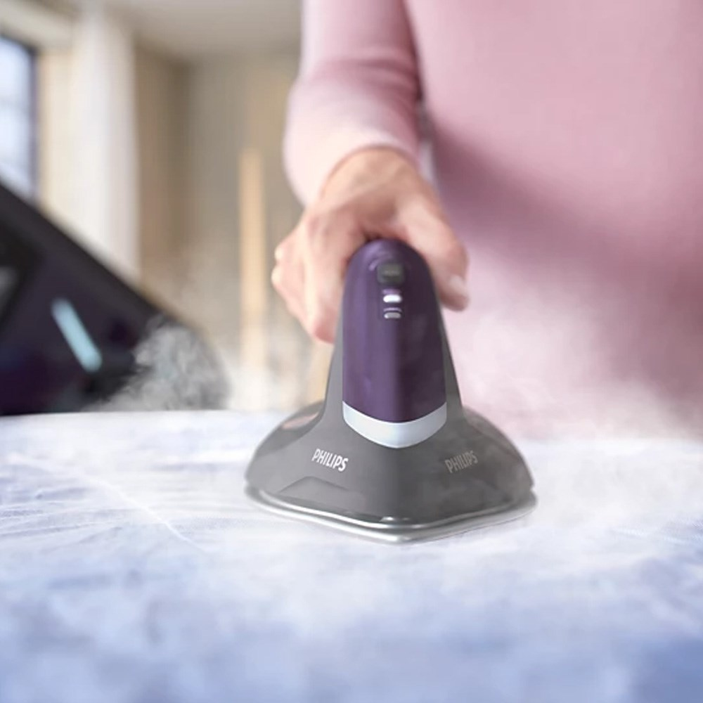 Bir kişi siyah ve mor Philips buharlı ütü kullanıyor, kumaşa buhar veriyor.