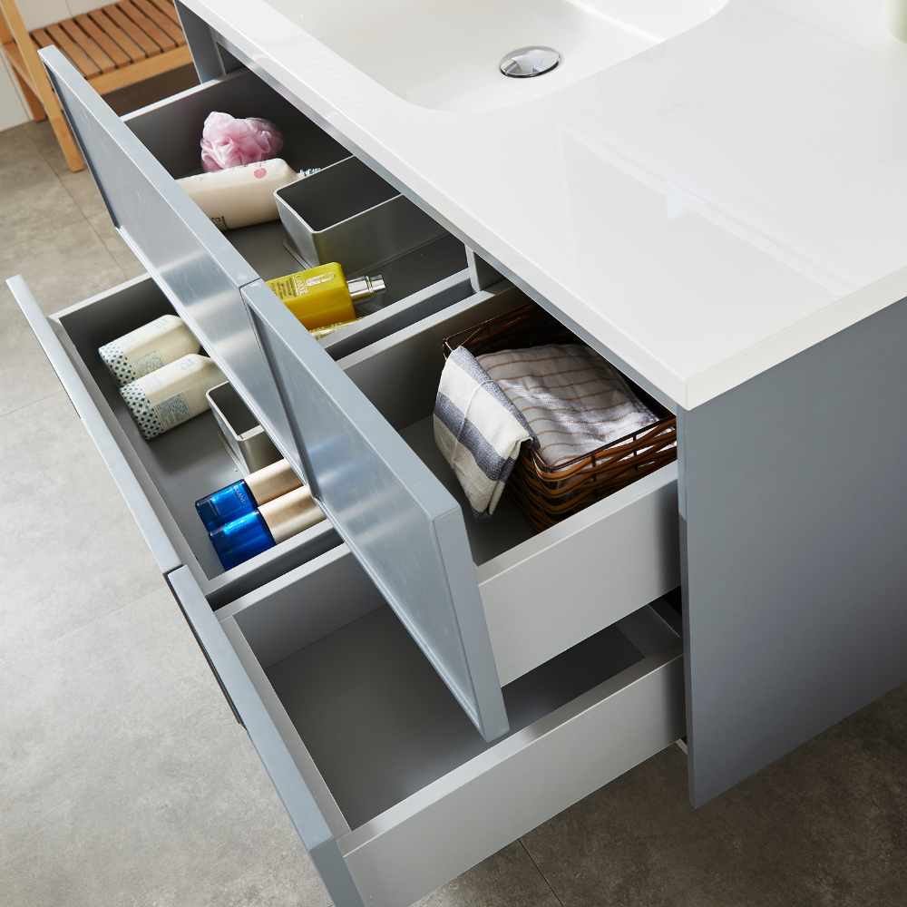 Un moderno mobile da bagno grigio con cassetti aperti, che mostra articoli da toeletta organizzati e asciugamani.