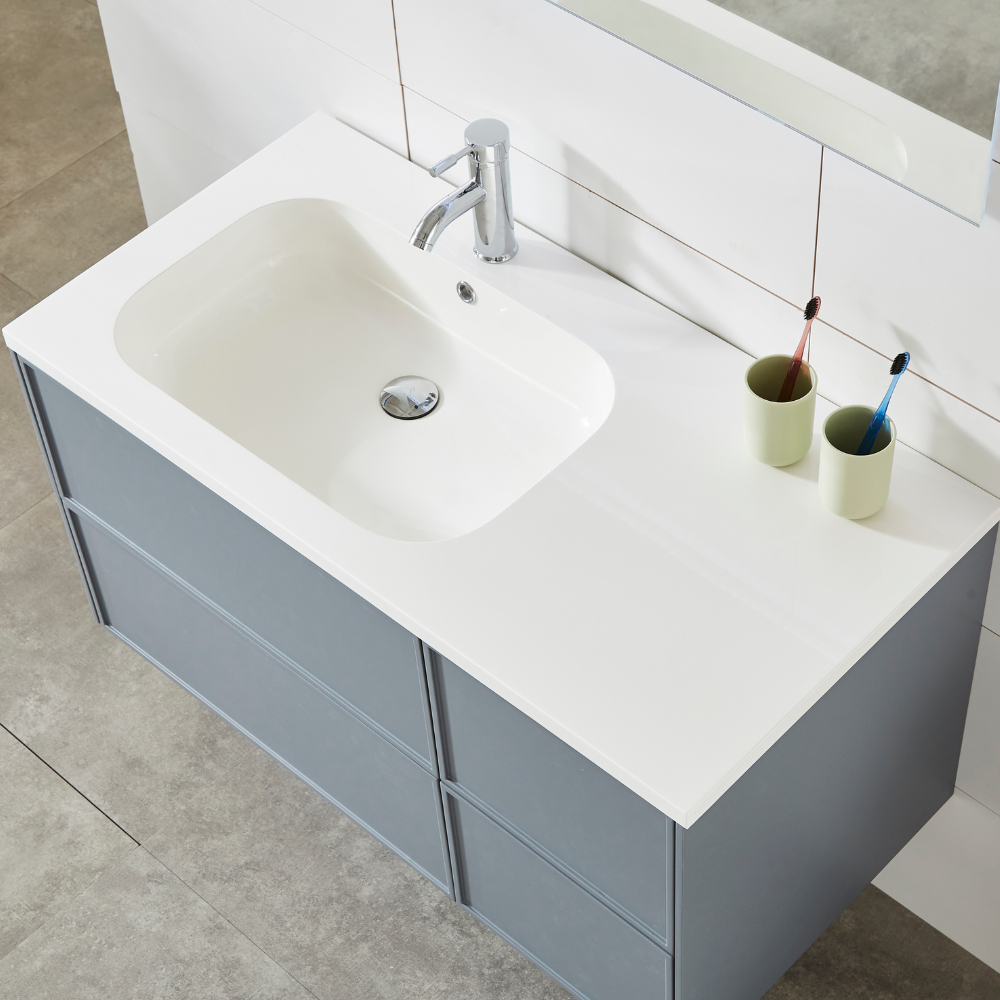 Moderno mobile da bagno grigio con piano bianco, lavabo integrato e due bicchieri con spazzolini.