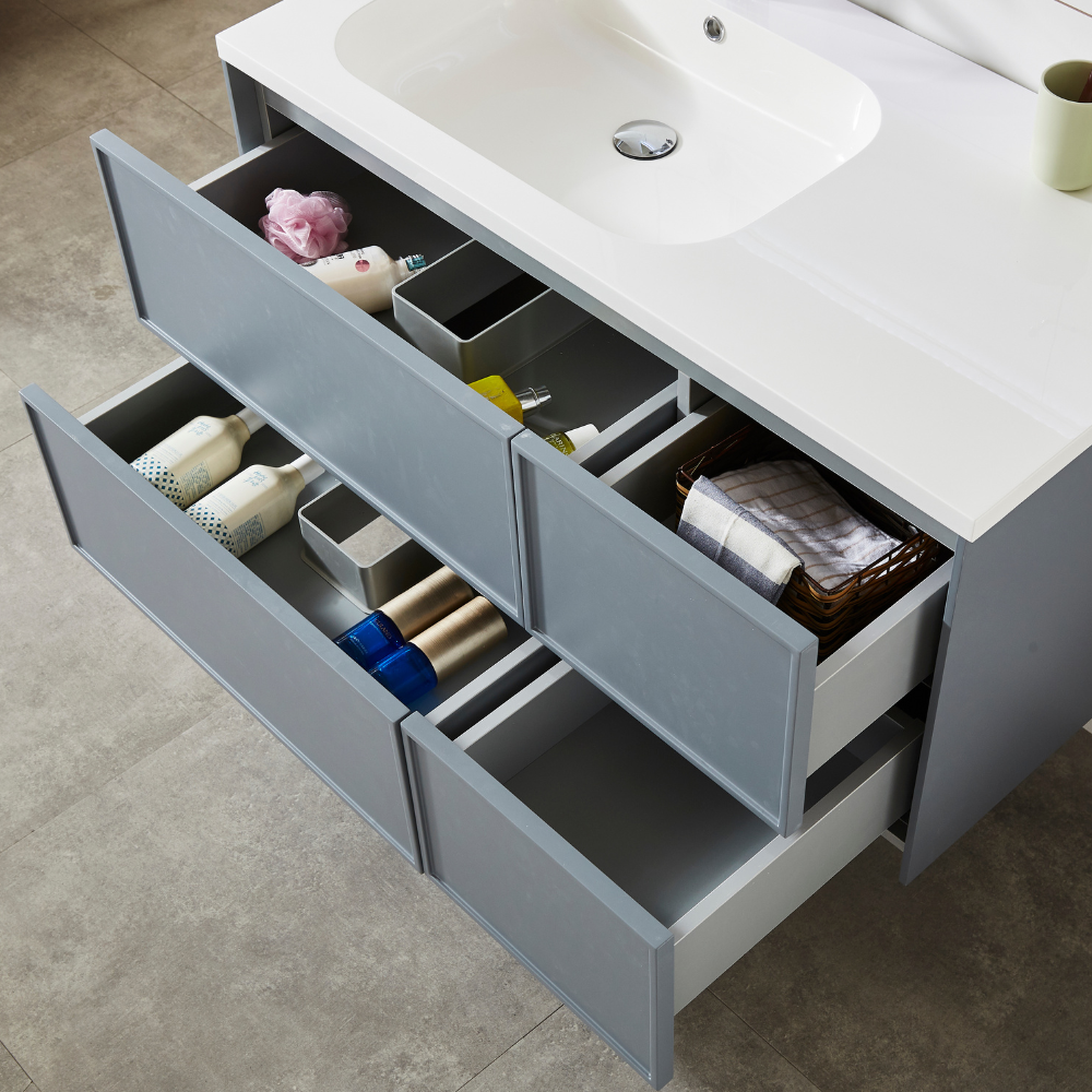 Mobile da bagno grigio con lavabo bianco e cassetti aperti pieni di articoli da toeletta e asciugamani.