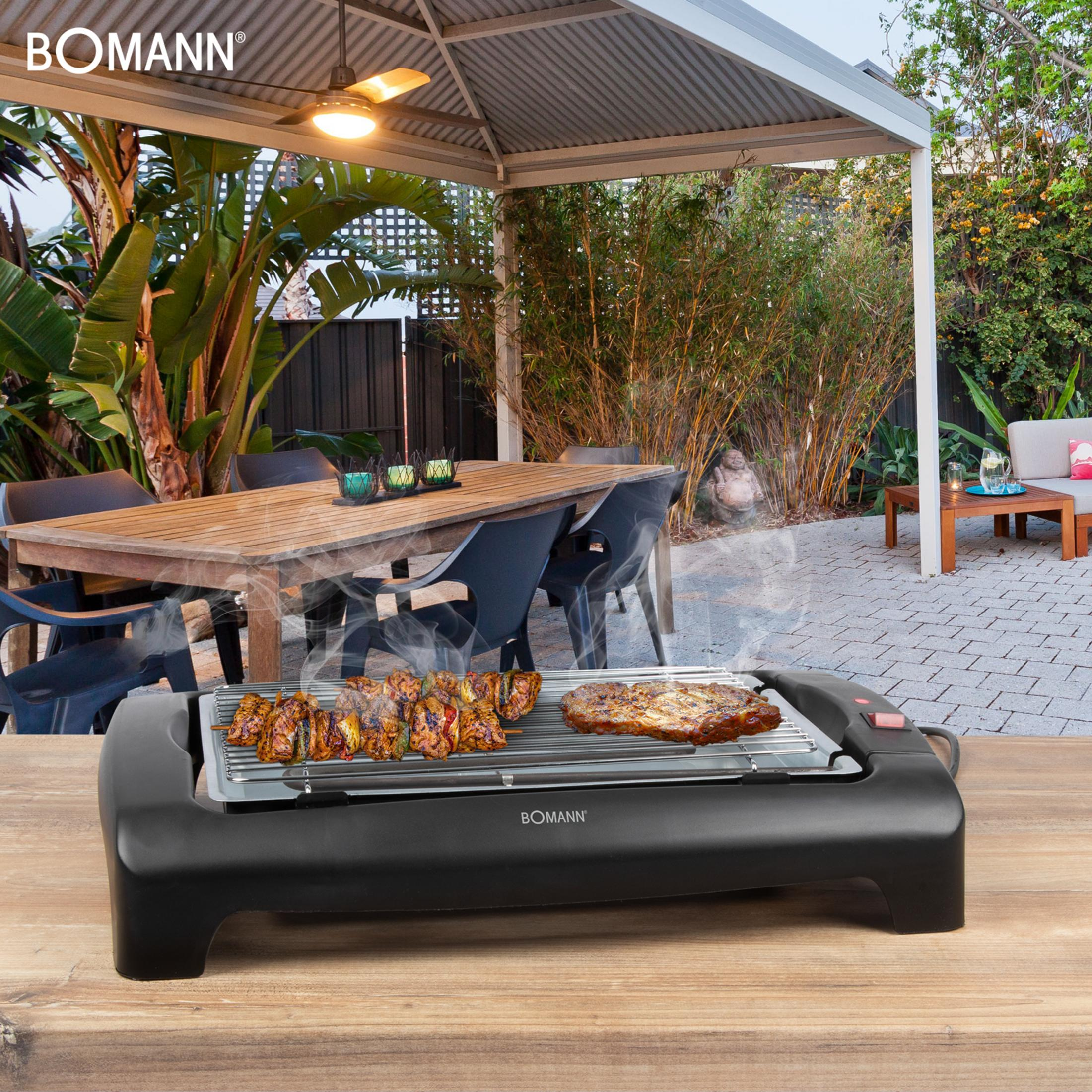 Un grill elettrico da tavolo con carne e spiedini su un patio in legno all'aperto.