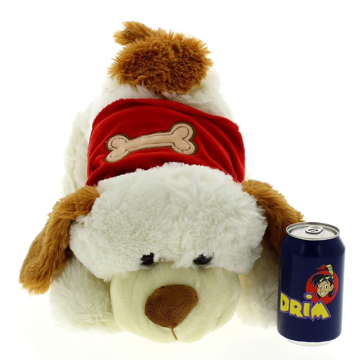 Un perro de peluche blanco y marrón con capa roja y un hueso, junto a una lata de refresco azul sobre fondo blanco.