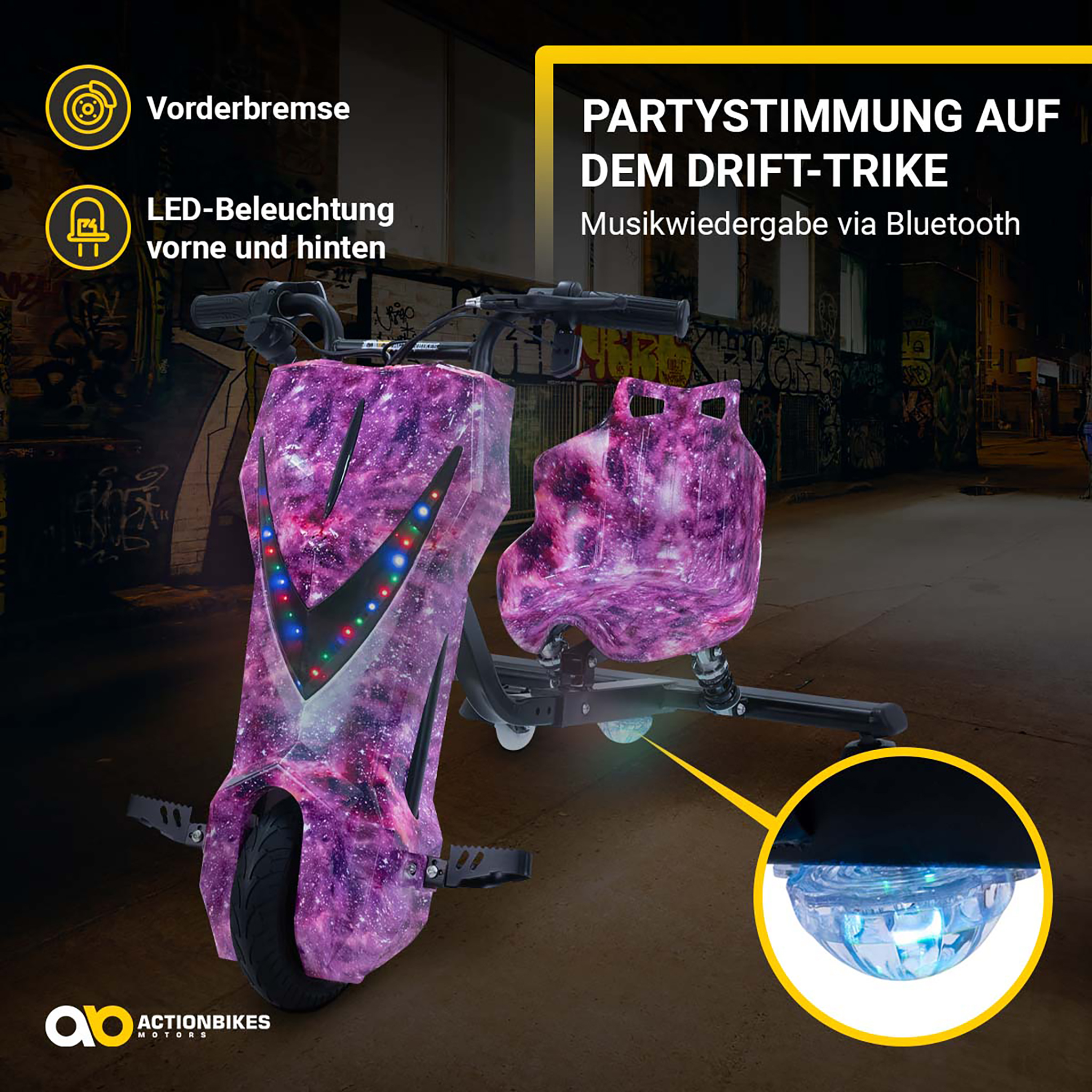 Lila Drift-Trike mit Galaxie-Muster, LED-Beleuchtung und Bluetooth-Musik, vor nächtlicher Graffiti-Wand.