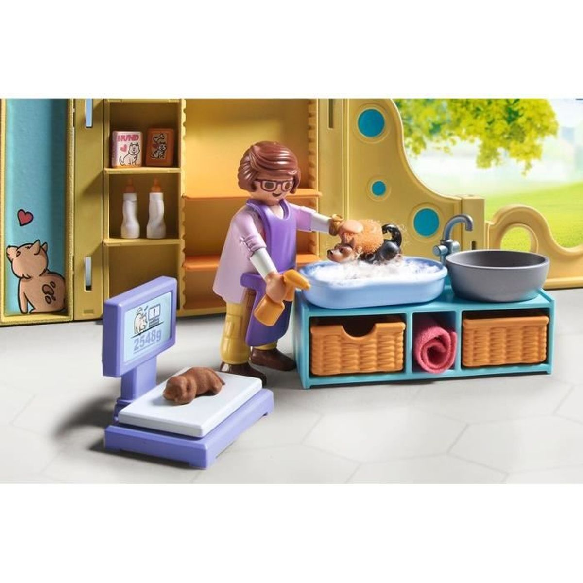 Figura de Playmobil lava un perro en una tina azul, con báscula y estantes al fondo.