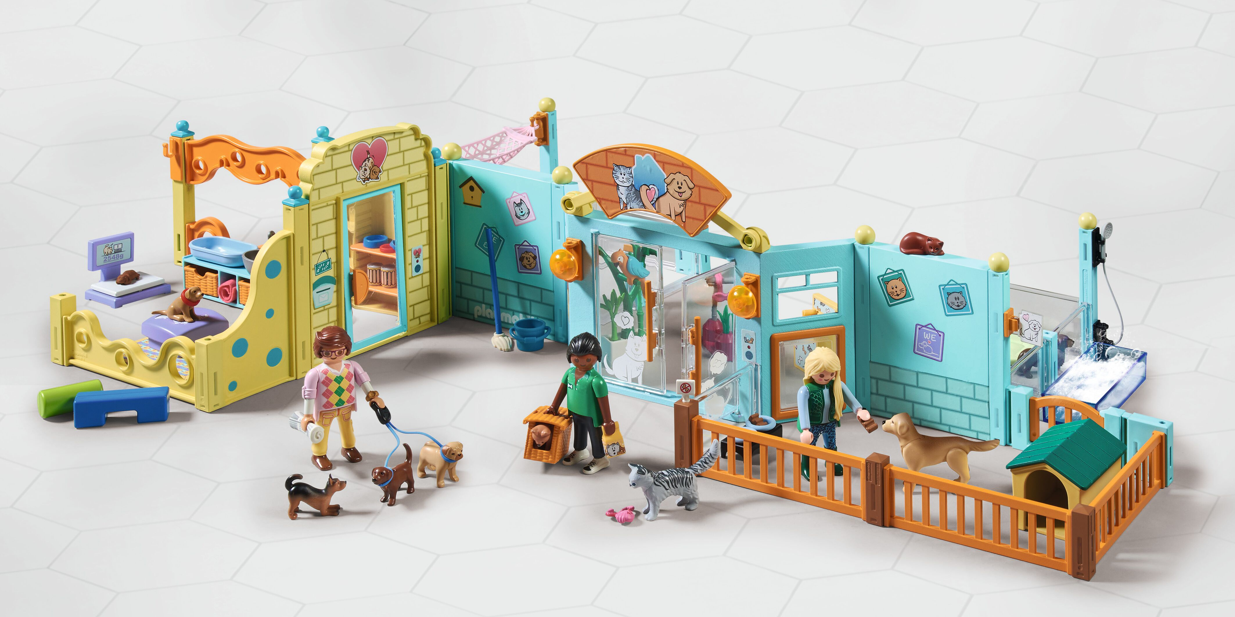 Set de juego de guardería de mascotas Playmobil con figuras, perros, gatos, vallas y edificios coloridos sobre fondo blanco.