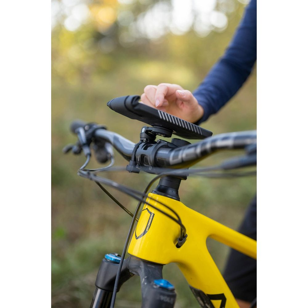 Un ciclista che interagisce con uno smartphone montato sul manubrio di una mountain bike gialla.
