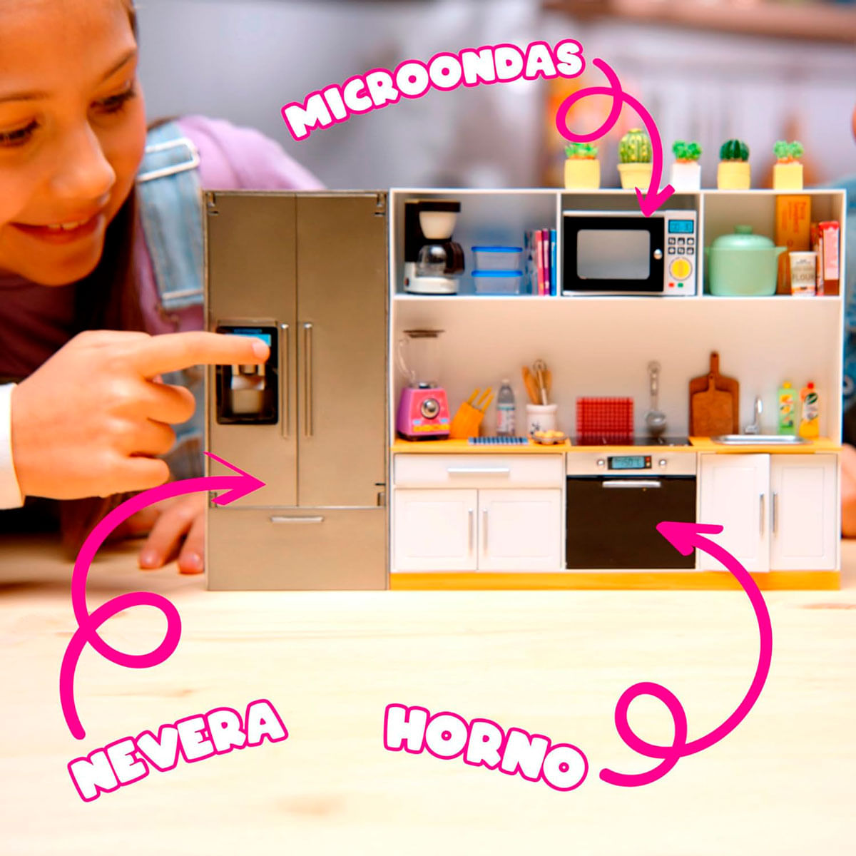 Un niño señala una cocinita de juguete con nevera, microondas y horno, etiquetada en español.