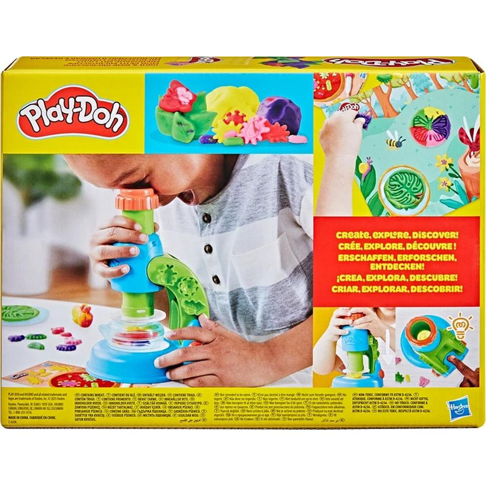 Un niño mira a través de un microscopio de juguete Play-Doh colorido en una caja con ejemplos.