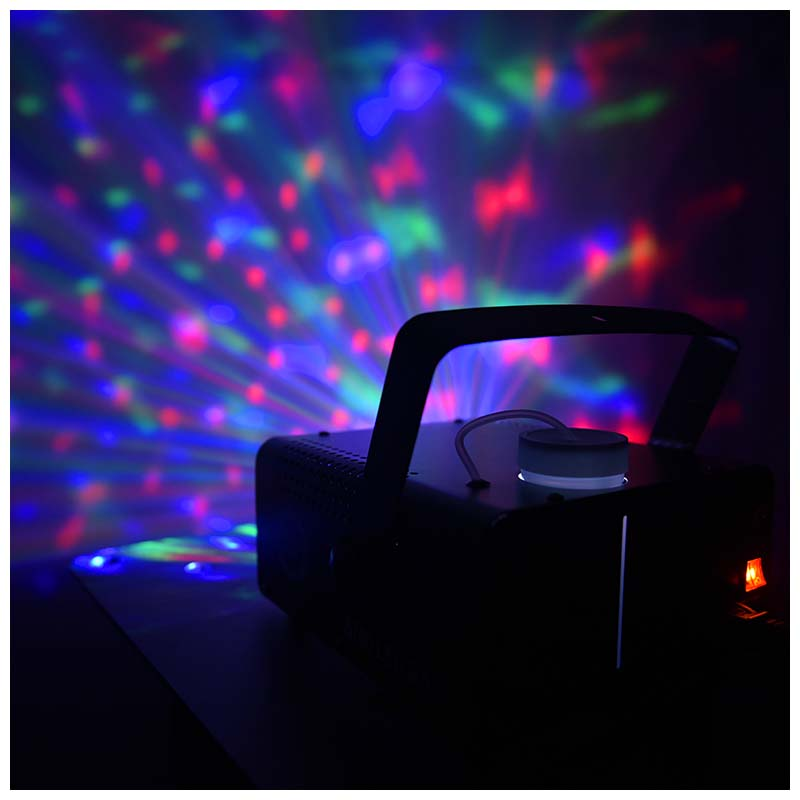 Eine schwarze Nebelmaschine projiziert bunte rote, blaue und grüne Lichtstrahlen auf eine Wand.