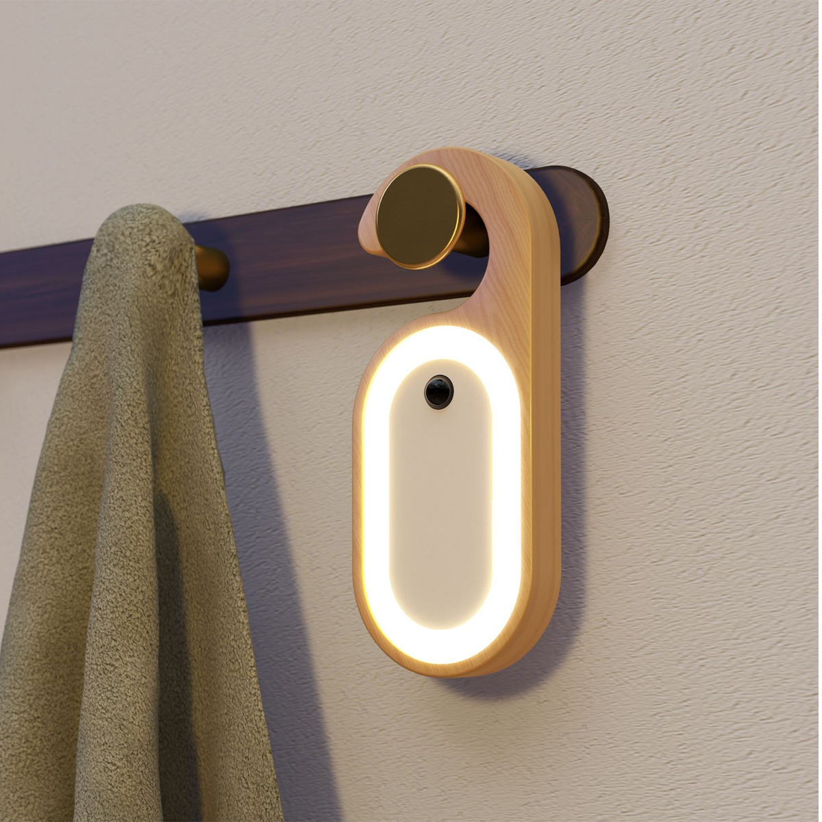 Eine ovale Holzlampe mit leuchtendem Rand hängt an einer Wandhalterung neben einem Handtuch.