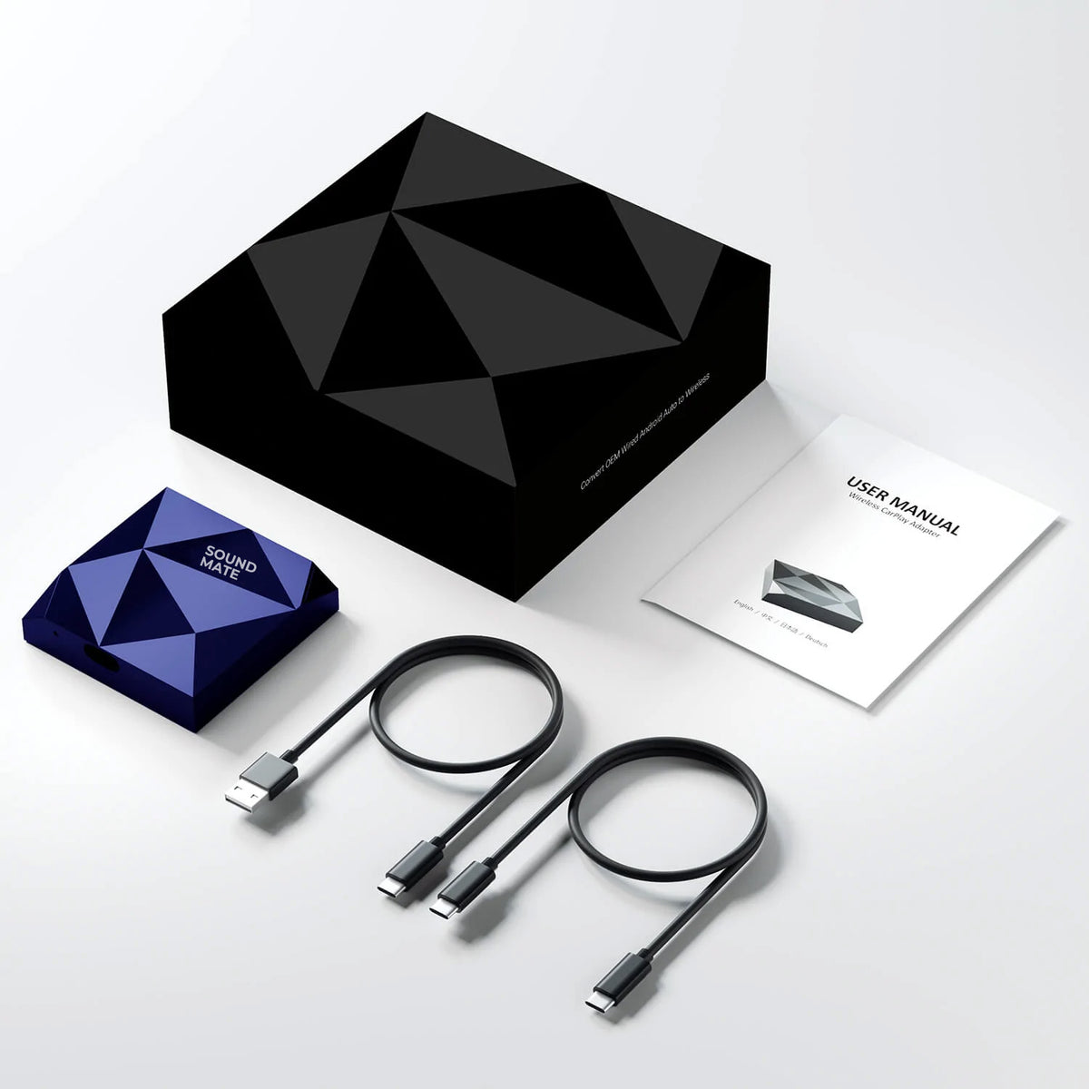 Ein Sound Mate Adapter, zwei USB-Kabel, ein Handbuch und eine schwarze Verpackungsbox auf weißem Grund.