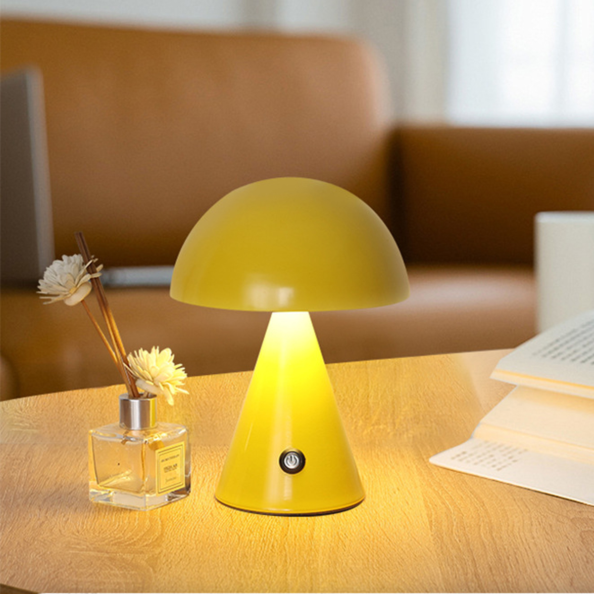 Eine kleine gelbe Pilzlampe steht auf einem Holztisch, neben einem Diffusor und einem offenen Buch.