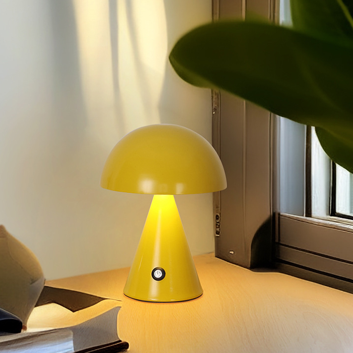 Eine kleine gelbe Pilzlampe auf einer Holztischplatte in der Nähe eines Fensters mit grünen Pflanzen.