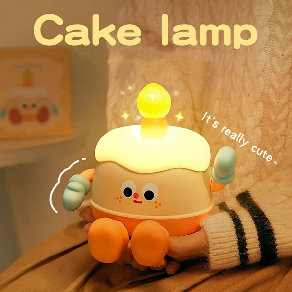 Eine süße, leuchtende Kuchen-Lampe mit Gesicht wird von einer Person gehalten.