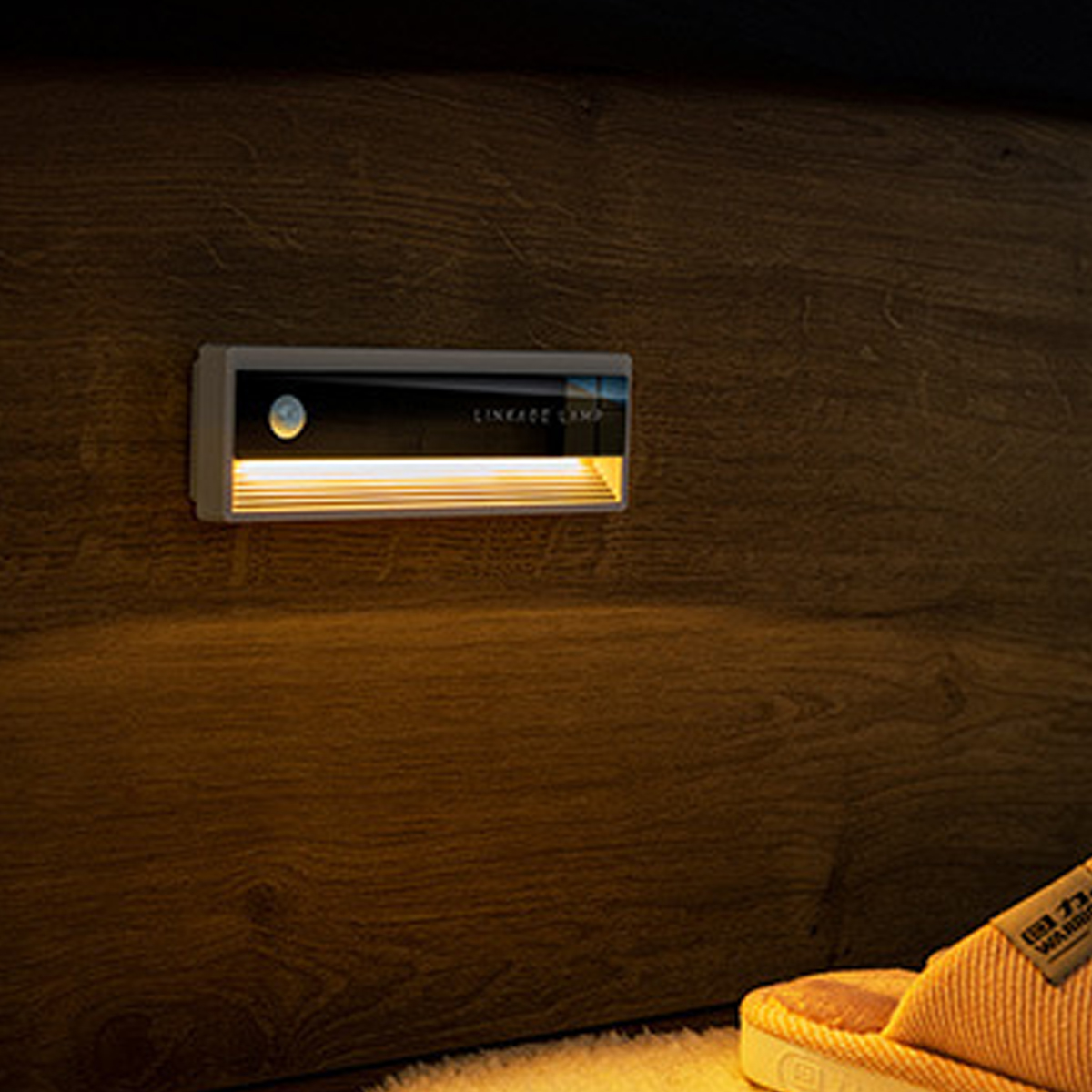 Eine kleine LED-Lampe mit warmem Licht ist an einer Holzwand montiert.