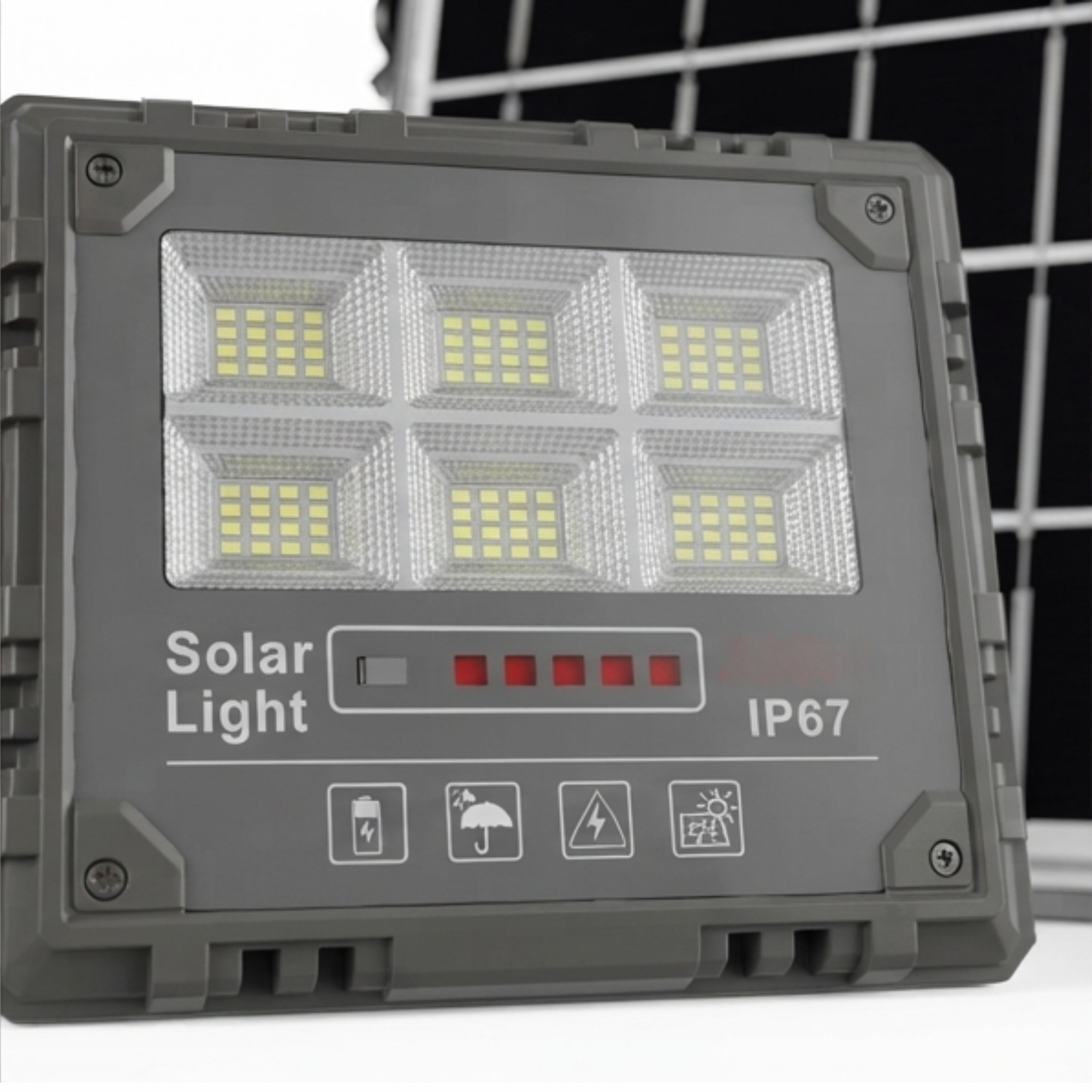 Un proyector solar gris con seis paneles LED, indicador de batería y clasificación IP67 frente a un panel solar.