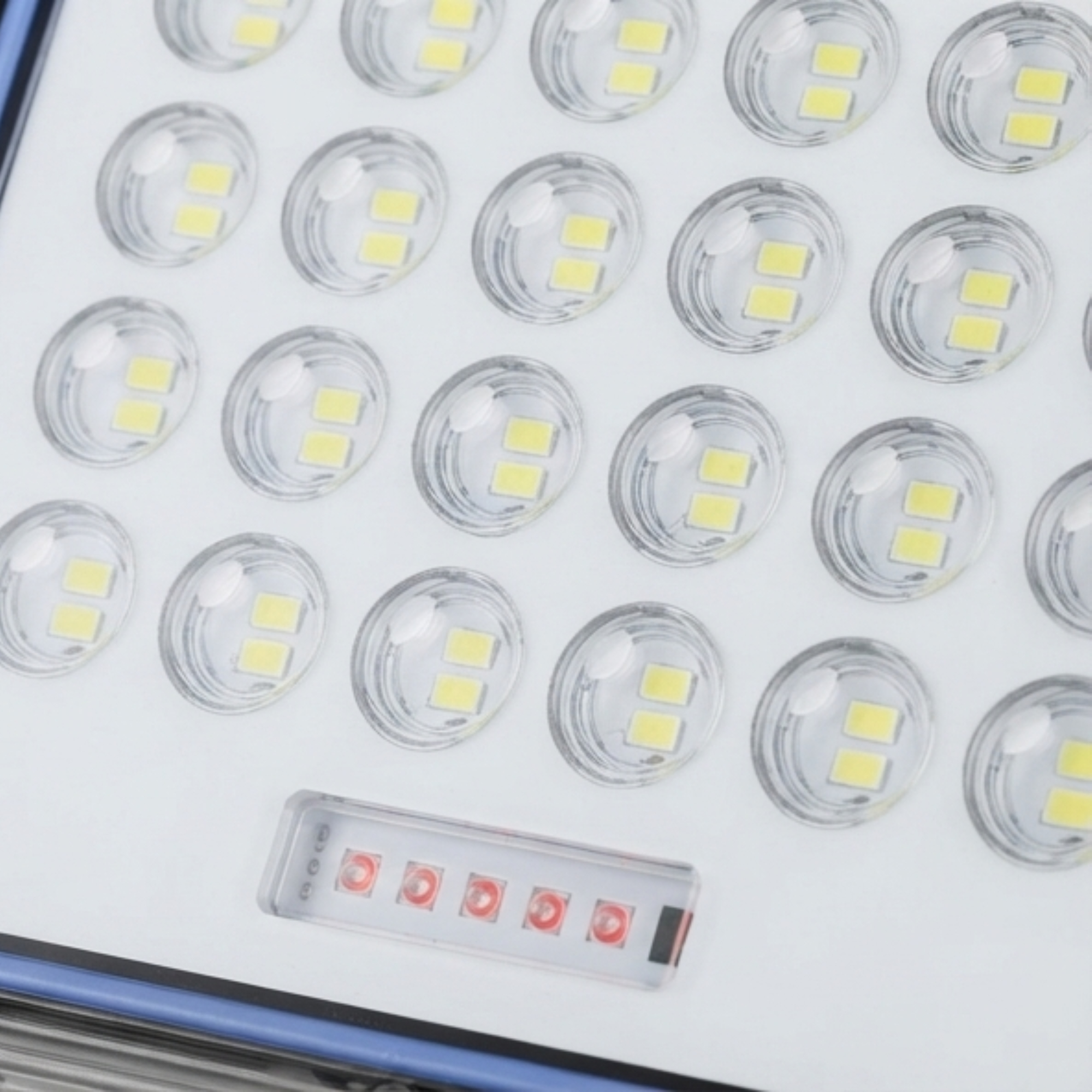 Primer plano de un panel LED blanco con una cuadrícula de pequeñas luces y una fila de cinco luces rojas.