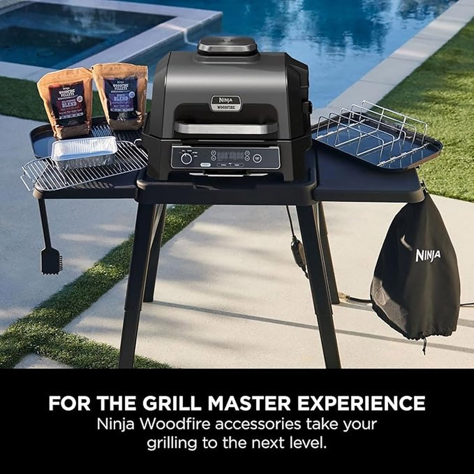 Un grill Ninja Woodfire su un supporto nero con accessori, vicino a una piscina.