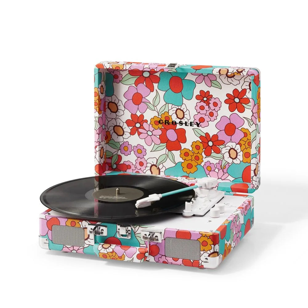 Ein bunter, retro Plattenspieler im Koffer-Design mit Blumenmuster, schwarzer Platte und weißem Tonarm.