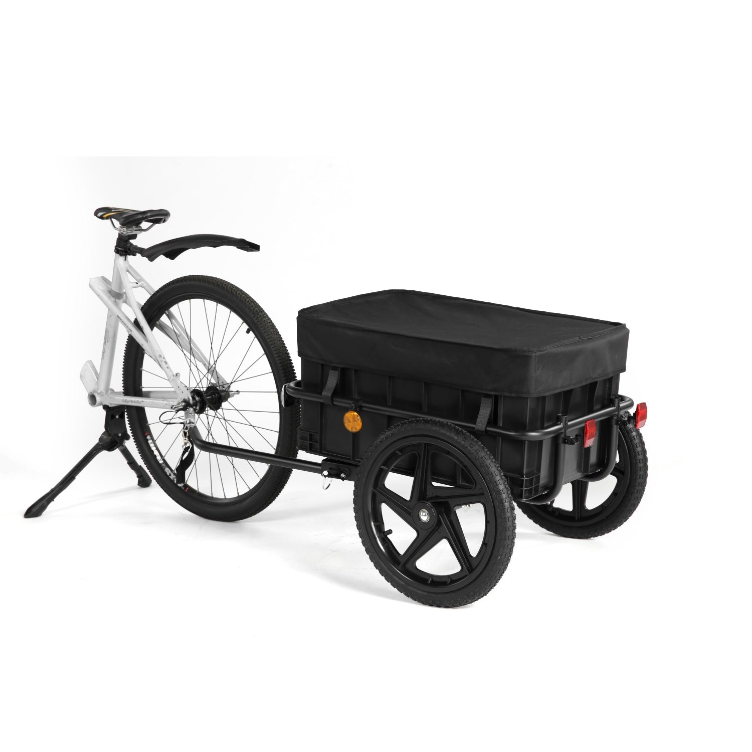 Una bicicleta plateada con soporte está acoplada a un gran remolque de carga negro con cajas integradas.