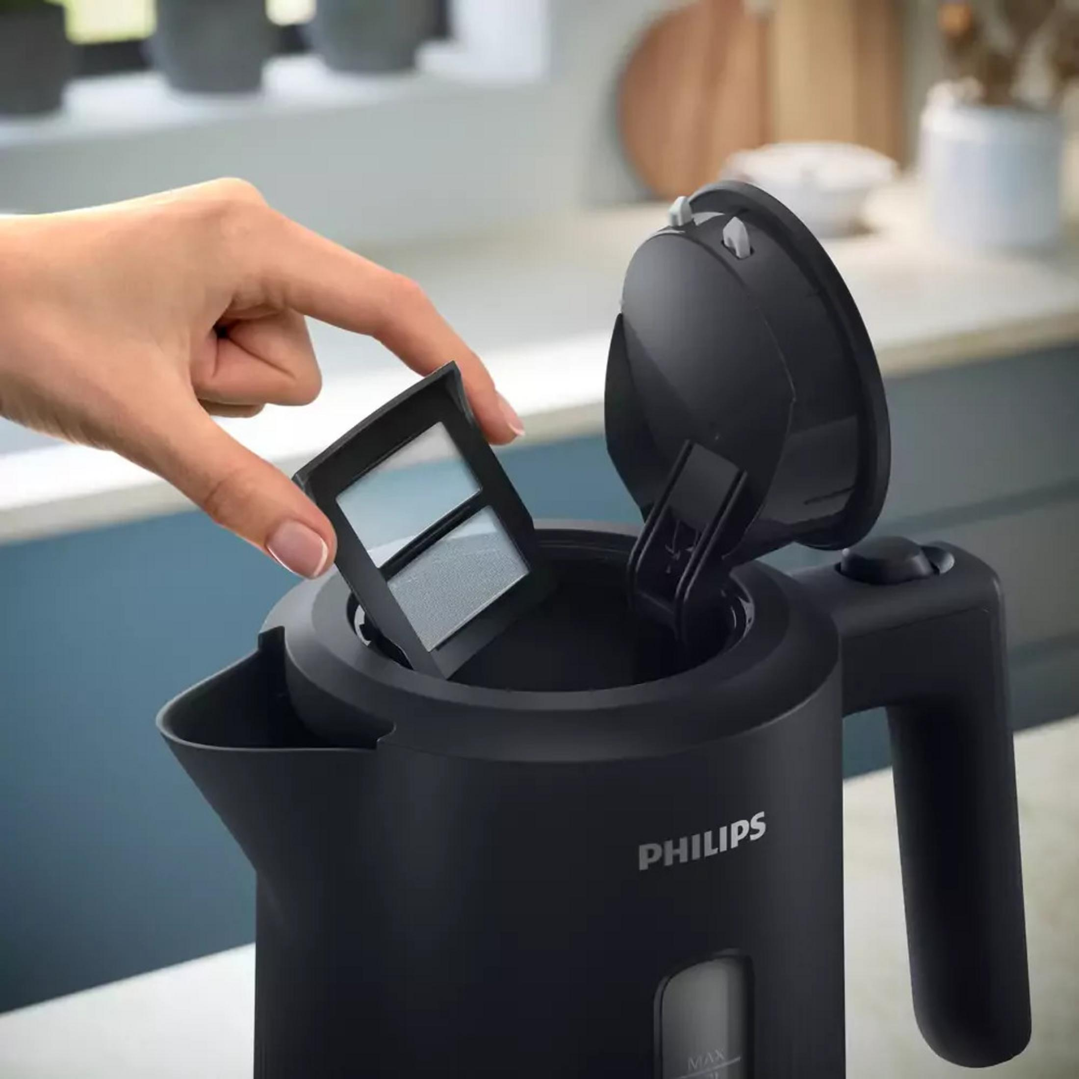 Una mano inserisce un filtro in un bollitore elettrico nero Philips.