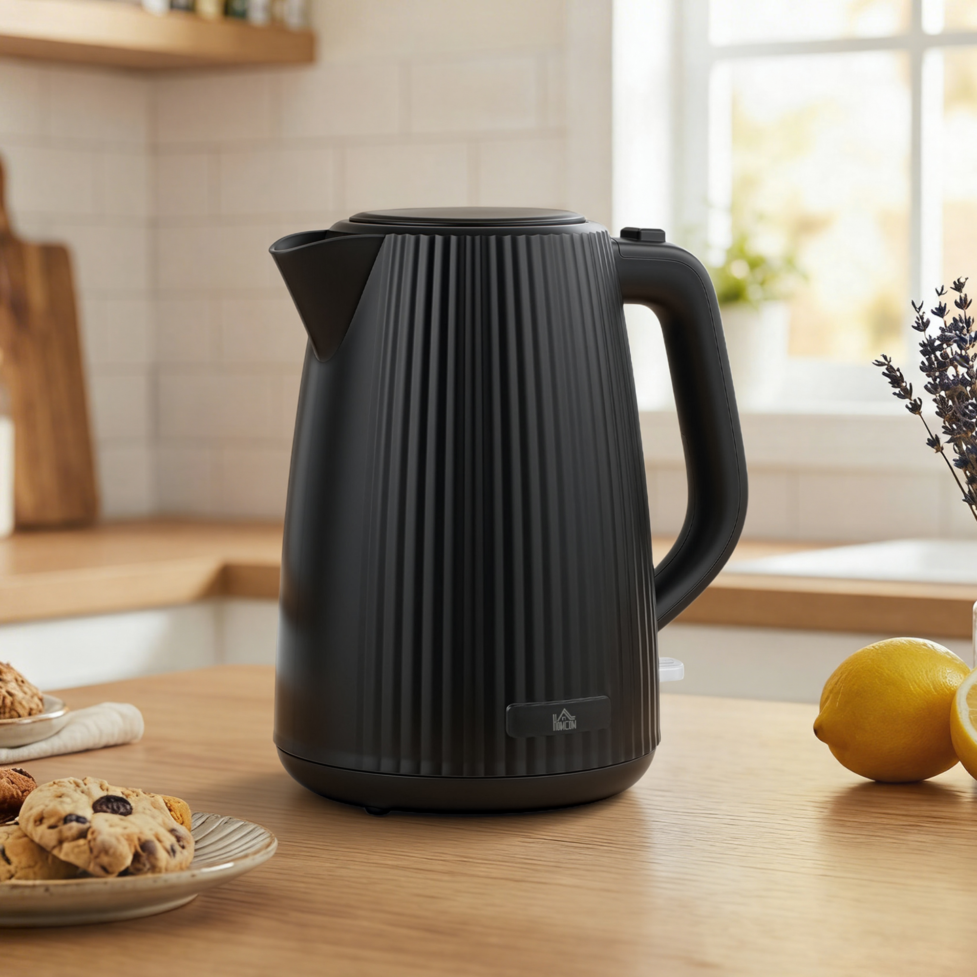 Un hervidor eléctrico negro mate con diseño acanalado se encuentra en una encimera de madera junto a limones y galletas.