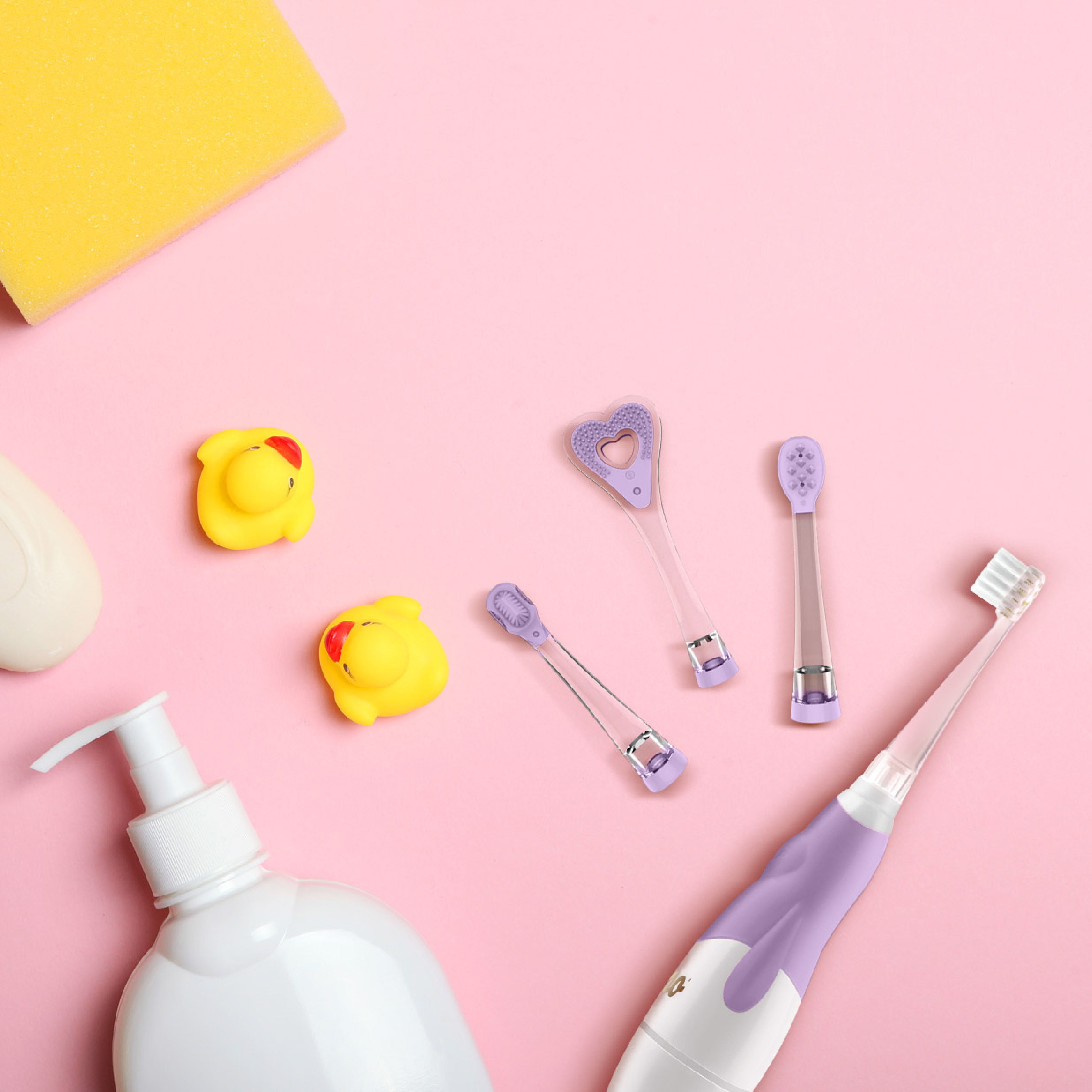 Ein rosa Hintergrund zeigt Babypflegeartikel: gelber Schwamm, Quietscheentchen, Seife, lila Zahnbürsten, Spender.