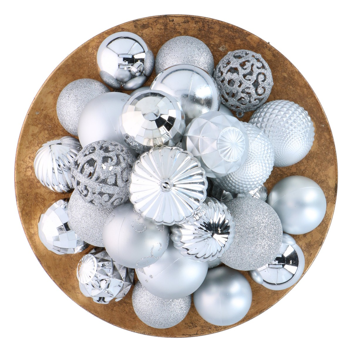 A round gold bowl filled with a variety of silver Christmas ornaments featuring different patterns and textures.