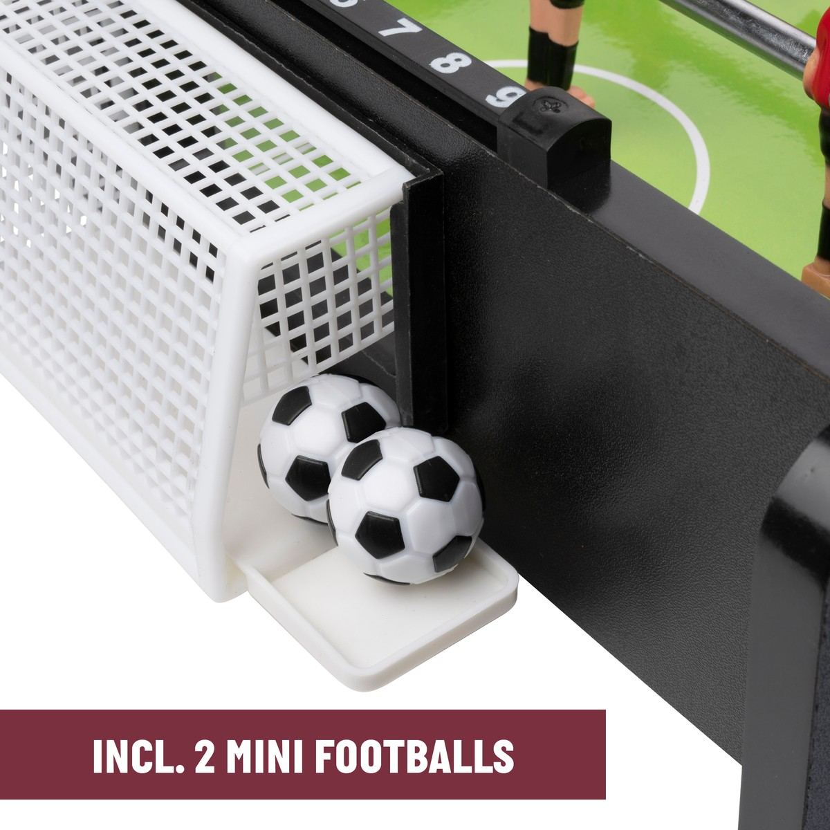 Deux mini ballons de football noir et blanc reposent dans le but et le bac d'un baby-foot.