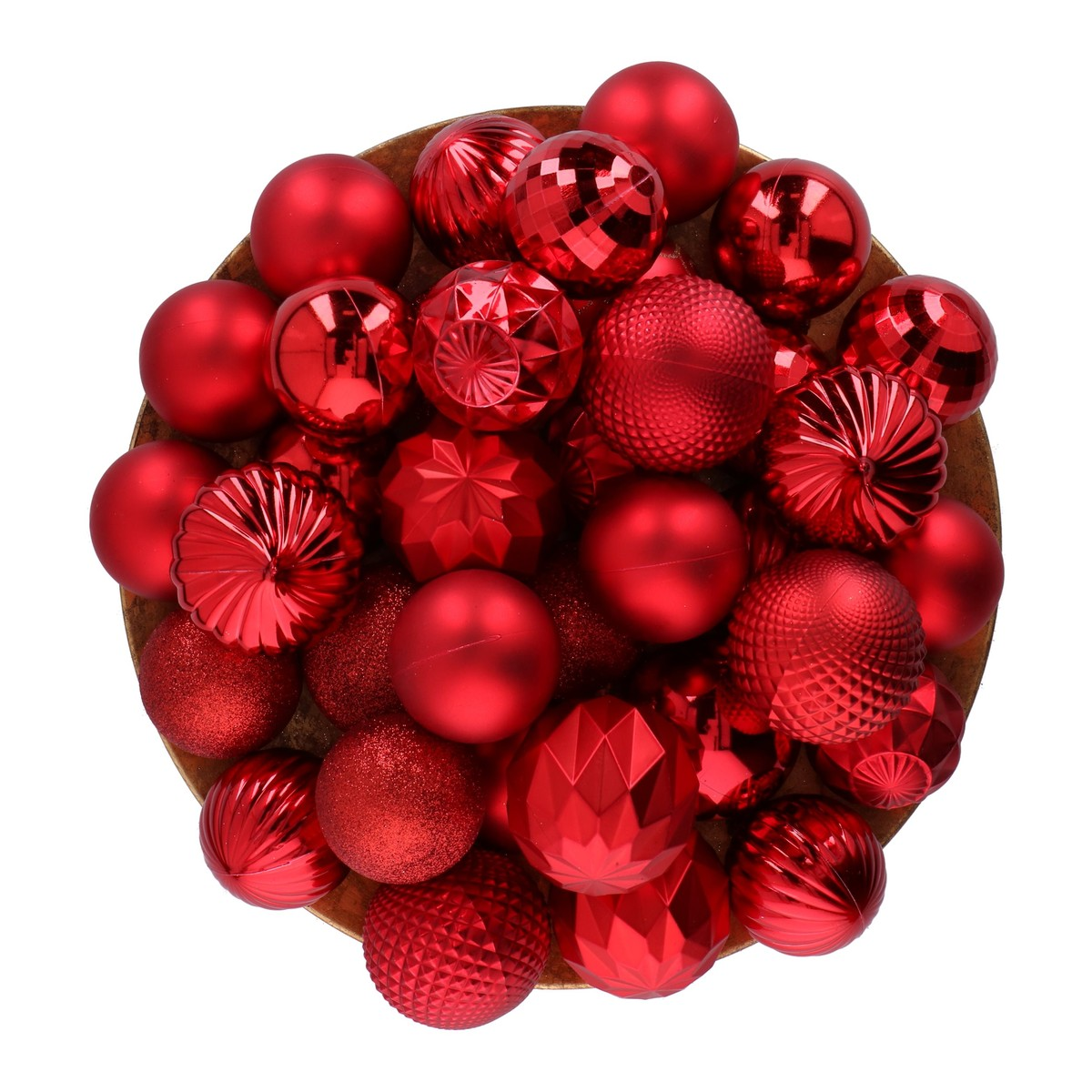 A wooden bowl filled with various shiny, matte, and textured red Christmas ornaments on a white background.
