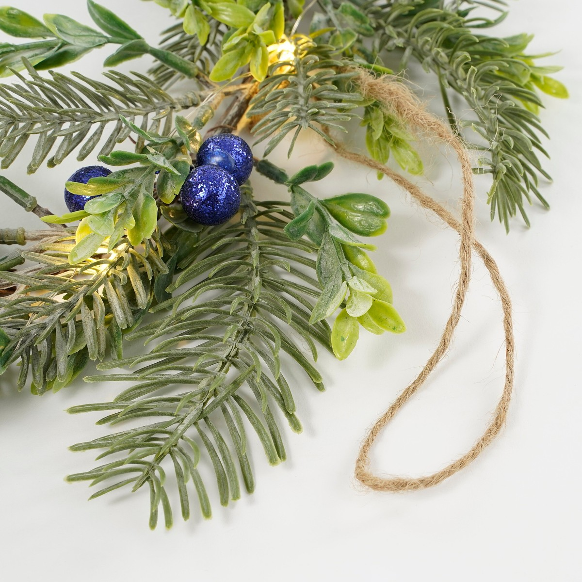 Green pine branches with glittery blue baubles and twine.