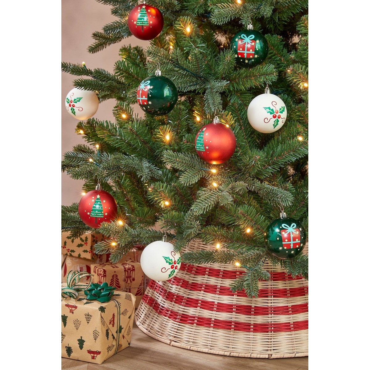 Decorated Christmas tree with red, green, and white ornaments, warm lights, wrapped gifts, and a striped basket base.