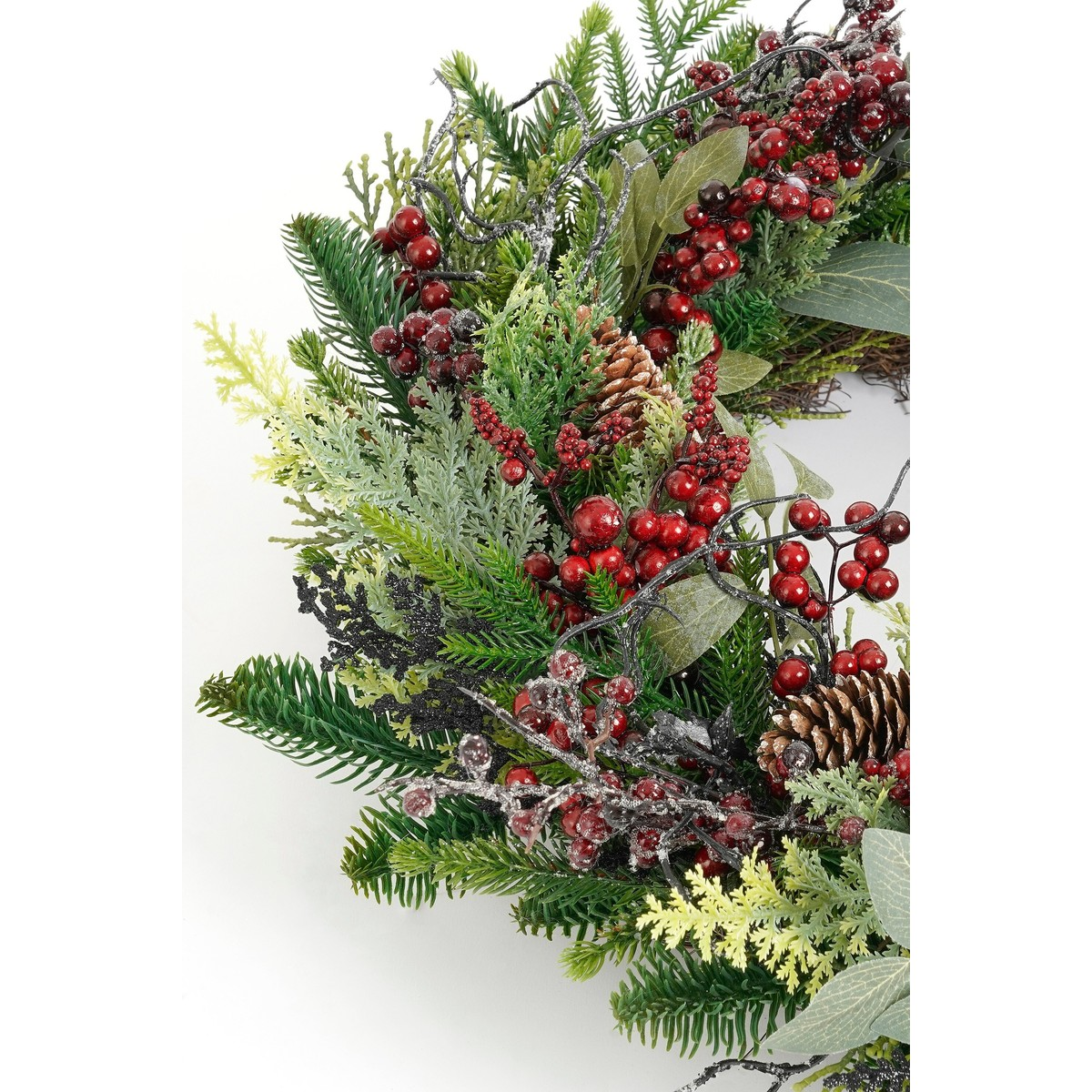 Christmas wreath featuring green branches, red berries, and pinecones on white.