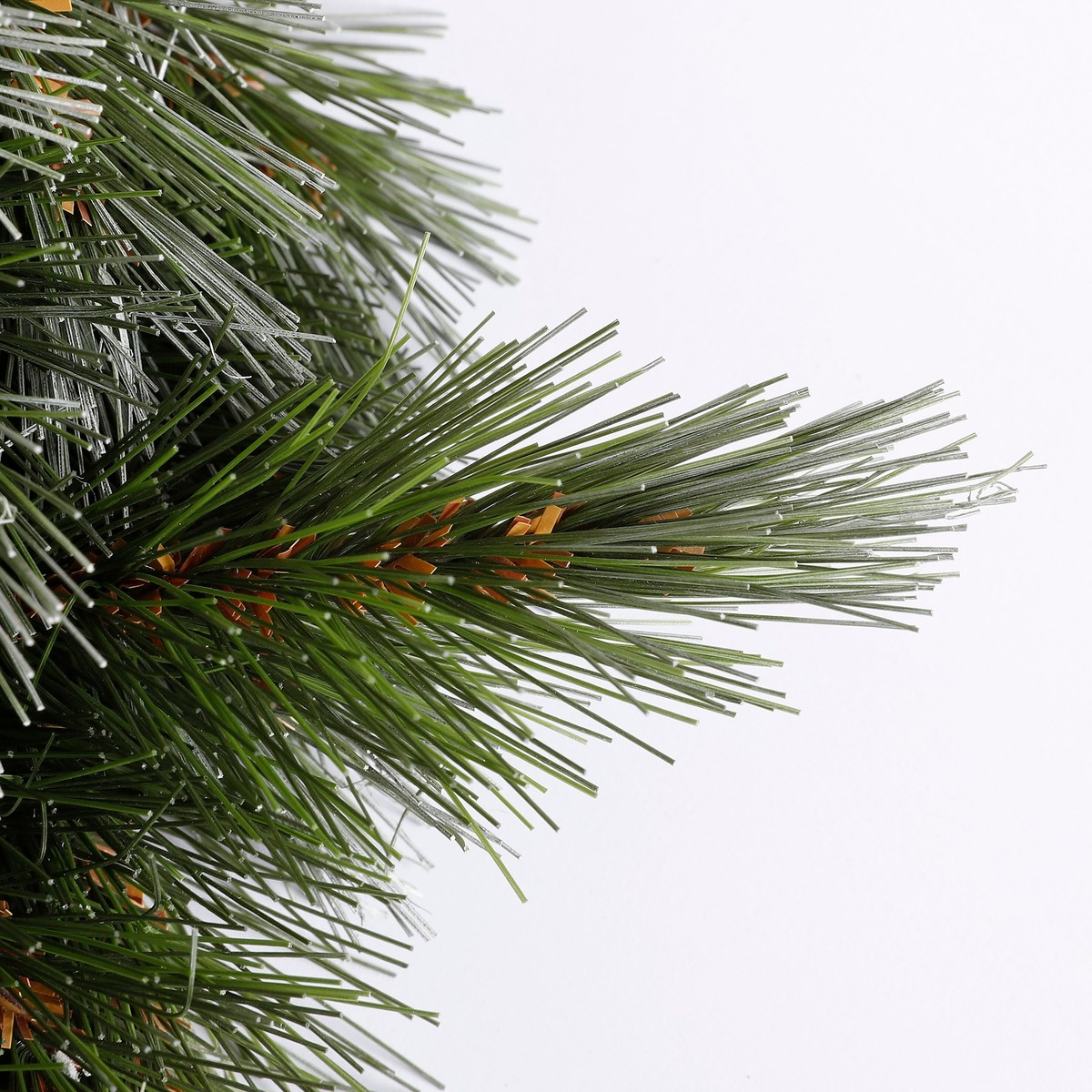 Green artificial pine branches with brown accents against a white background.