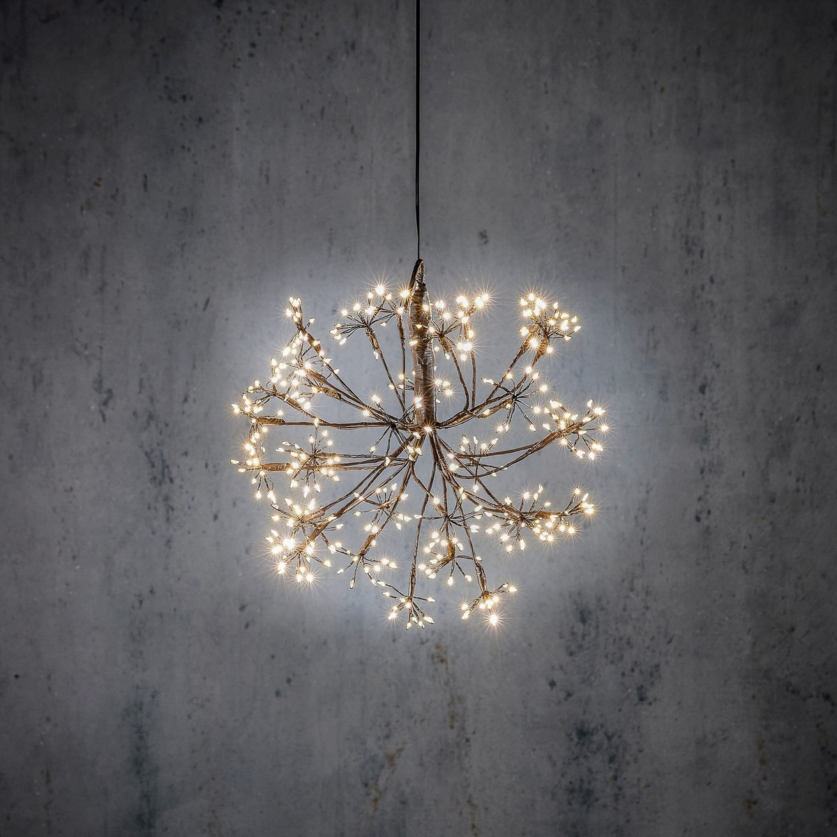 A hanging wire pendant lamp with many small lights against a grey wall.
