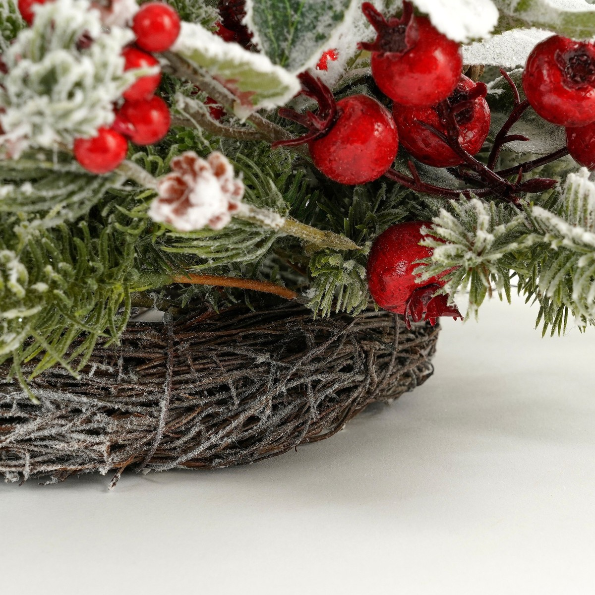 A frosty Christmas wreath with green pine, red berries, and brown twigs.