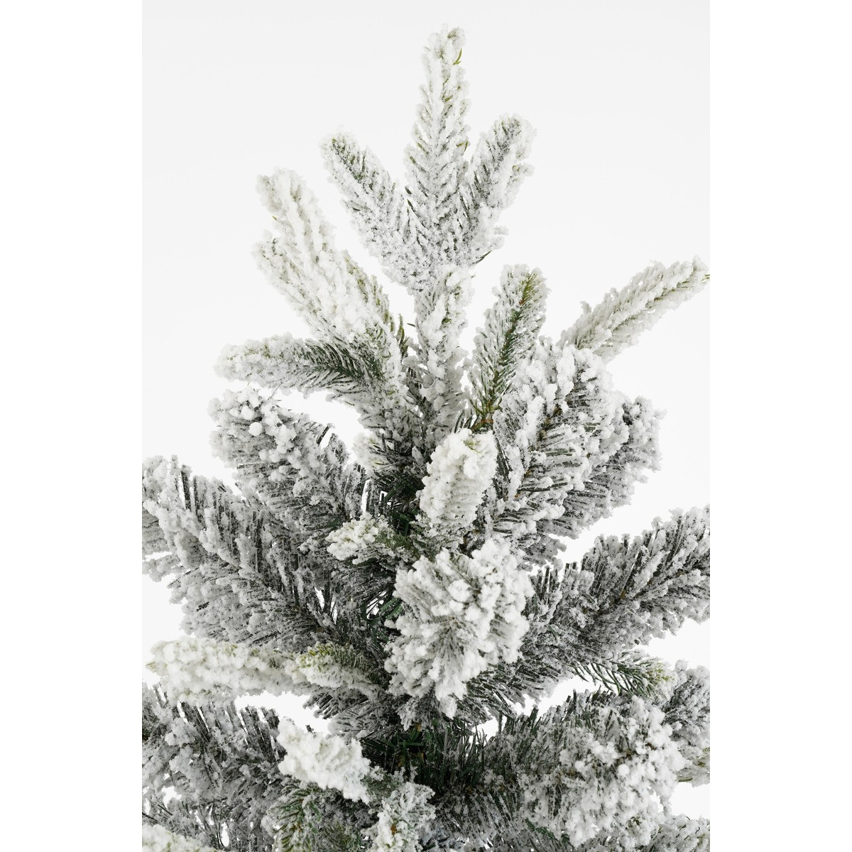 Close-up of snow-covered branches of an artificial Christmas tree against a white background.