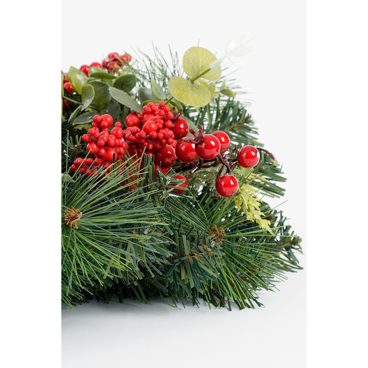 A festive wreath with green pine needles, red berries, and leaves on a white background.