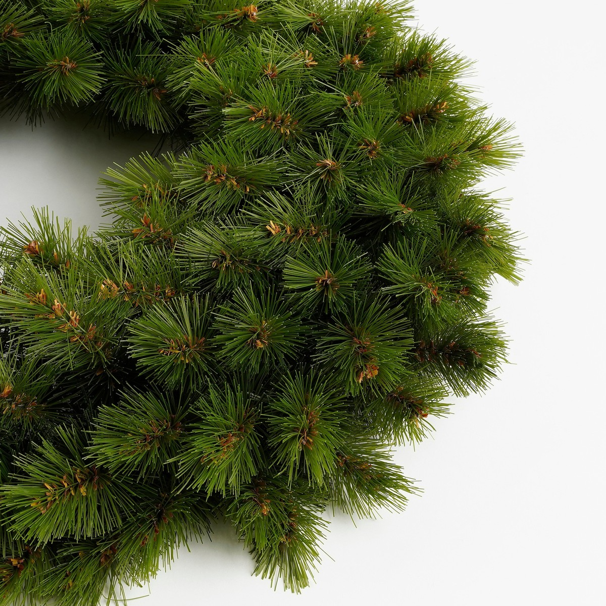 A green artificial pine wreath on a white background.