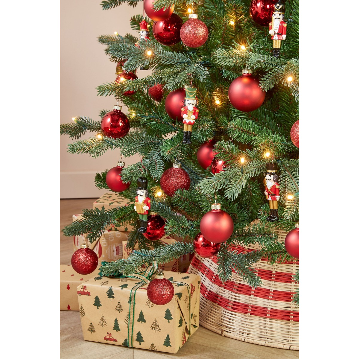 A decorated Christmas tree with red baubles, nutcracker ornaments, and wrapped gifts underneath.