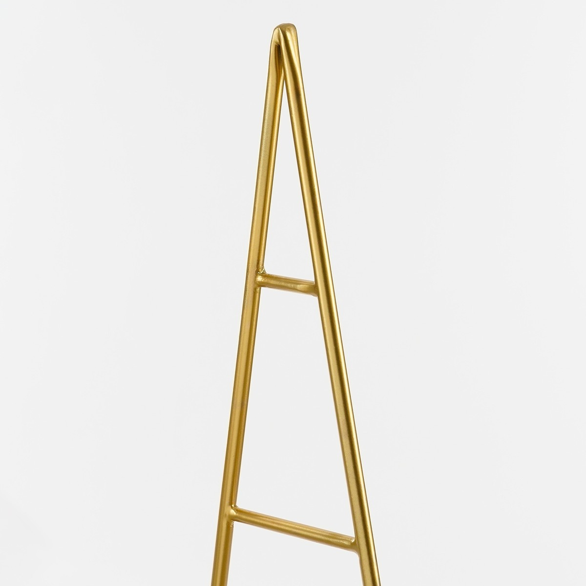 A minimalist, gold-colored metal stand shaped like a triangle against a white background.
