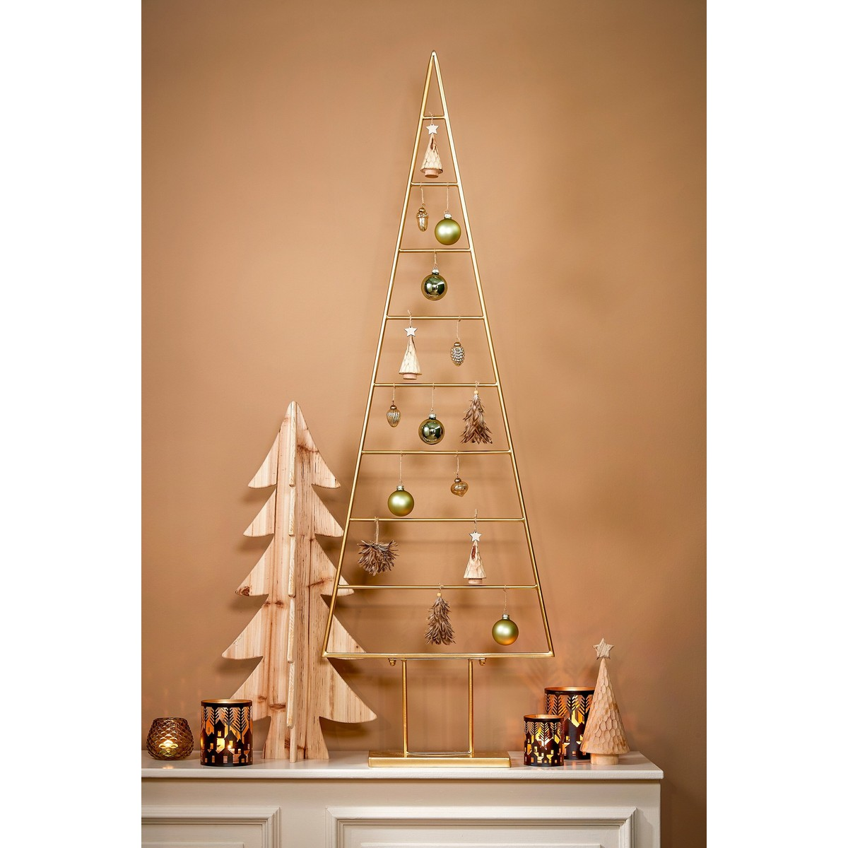 Modern Christmas decor featuring a gold wire tree, a wooden tree, and lit candles on a white cabinet.